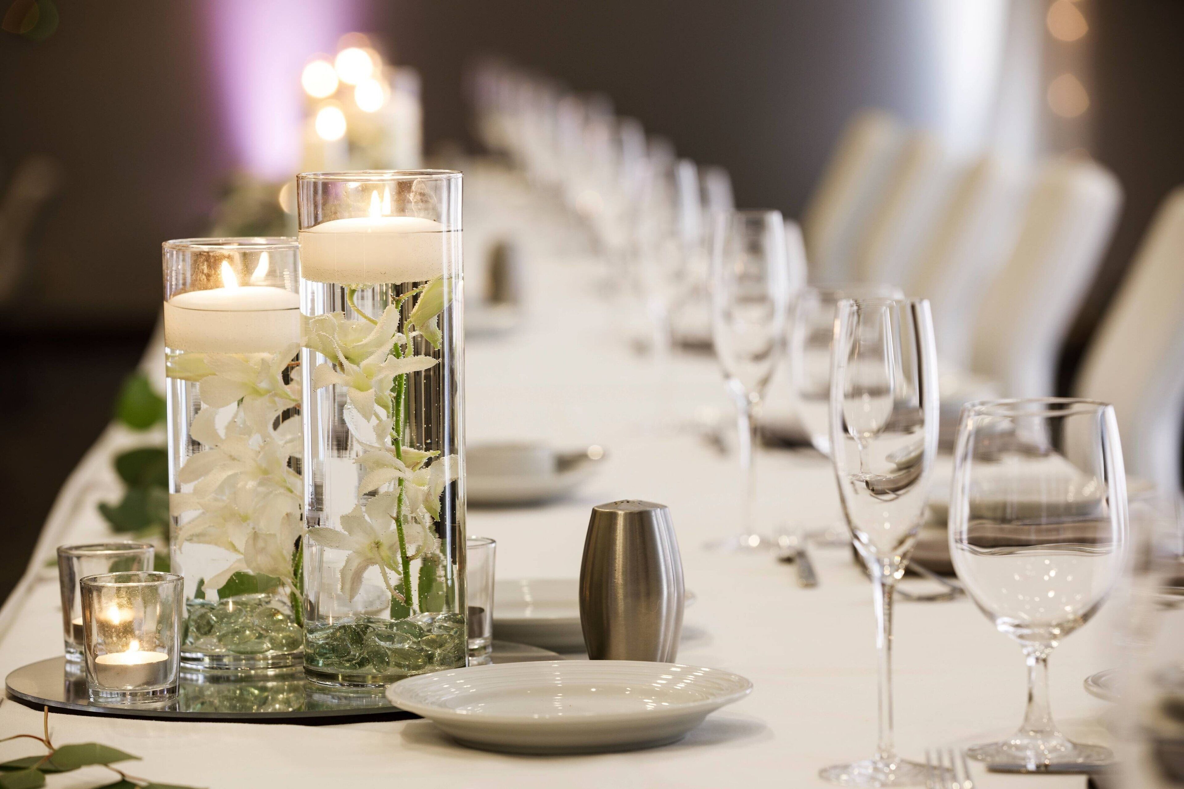 A table set for a formal event with candles, glassware, and floral arrangements.