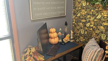 A workspace with a desk, computer, keyboard, and decorative items including a pumpkin and a scarecrow. A motivational quote is displayed on the wall.
