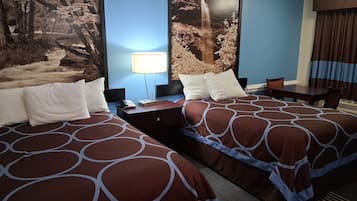 A hotel room with two beds, a desk, a chair, a lamp, and a large wall mural of a waterfall.