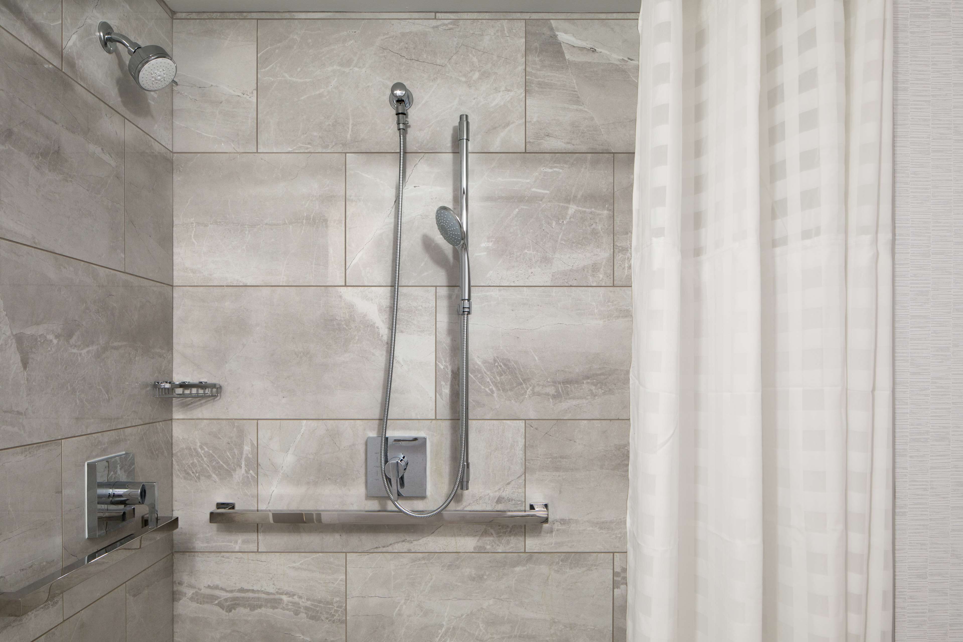 A modern bathroom with a shower, a towel rack, and a built-in soap dispenser.