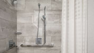 A modern bathroom with a shower, a towel rack, and a built-in soap dispenser.
