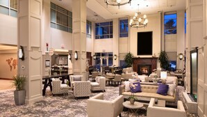 A spacious lobby with multiple seating areas, a fireplace, and large windows. - Embassy Suites by Hilton Portland Maine (Portland)