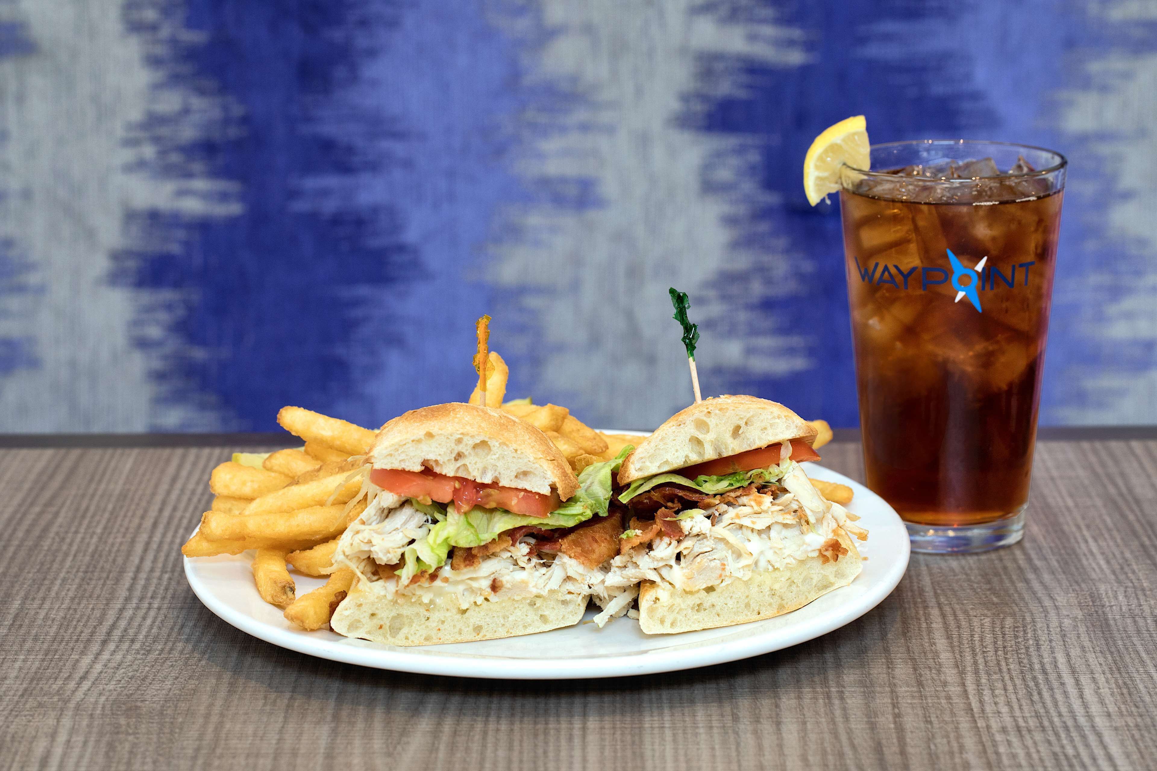 A plate with a sandwich and fries, and a glass of iced tea.
