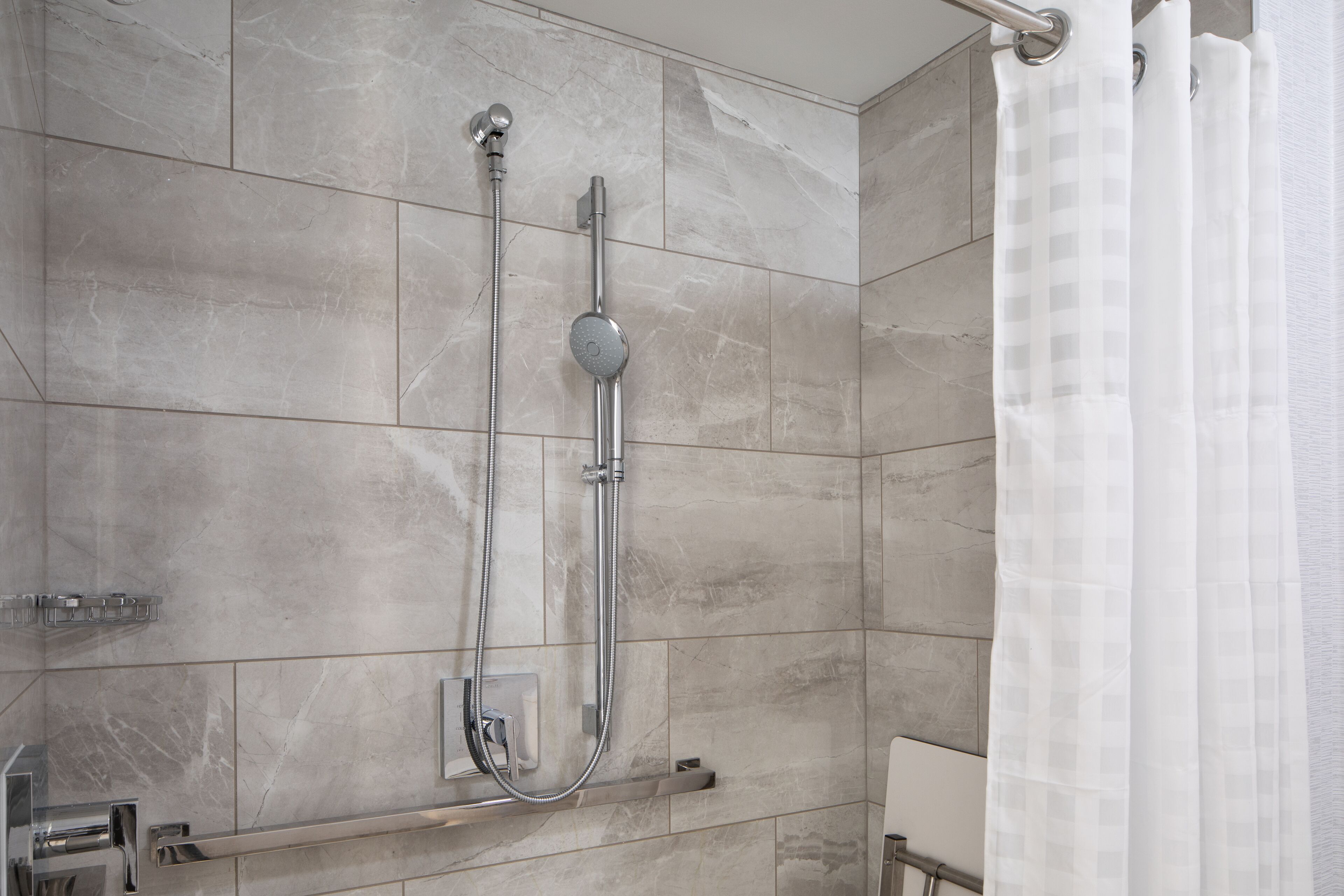 Un baño moderno con ducha, paredes de azulejos y puerta de vidrio.