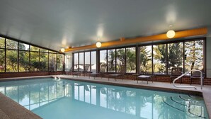 A swimming pool with clear blue water, surrounded by lounge chairs and a brick wall. - Embassy Suites by Hilton Portland Maine (Portland)