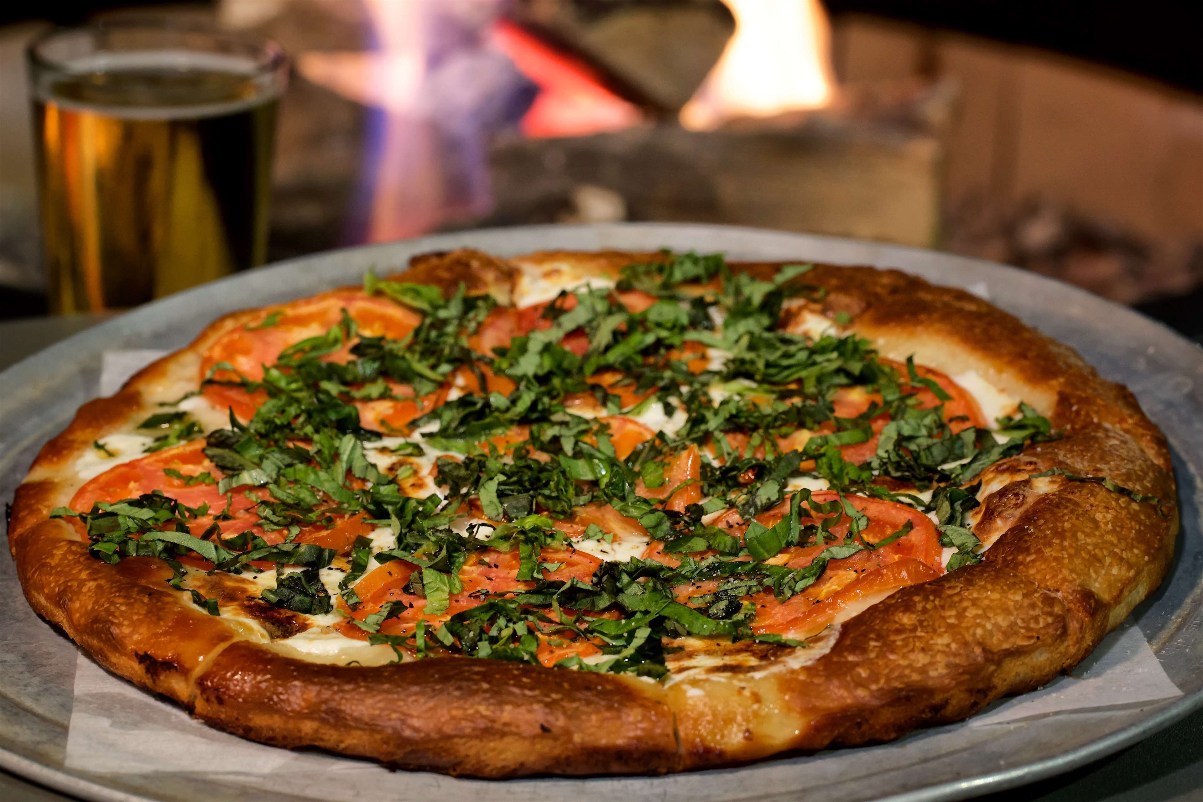 Pizza com cobertura em uma assadeira de metal.
