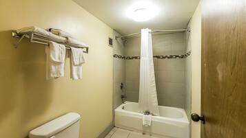 A bathroom with a toilet, a bathtub with a shower curtain, and a towel rack.