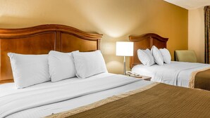 Habitació d'hotel amb dos llits, una nitlínia amb una làmpada i una cadira.
