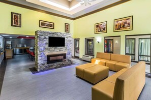 A spacious living area with a stone fireplace, yellow walls, and modern furniture. - Rodeway Inn Knoxville East (Knoxville)