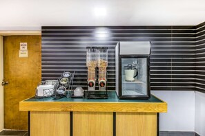A coffee station with a coffee machine, grinder, and a glass container with coffee beans.
