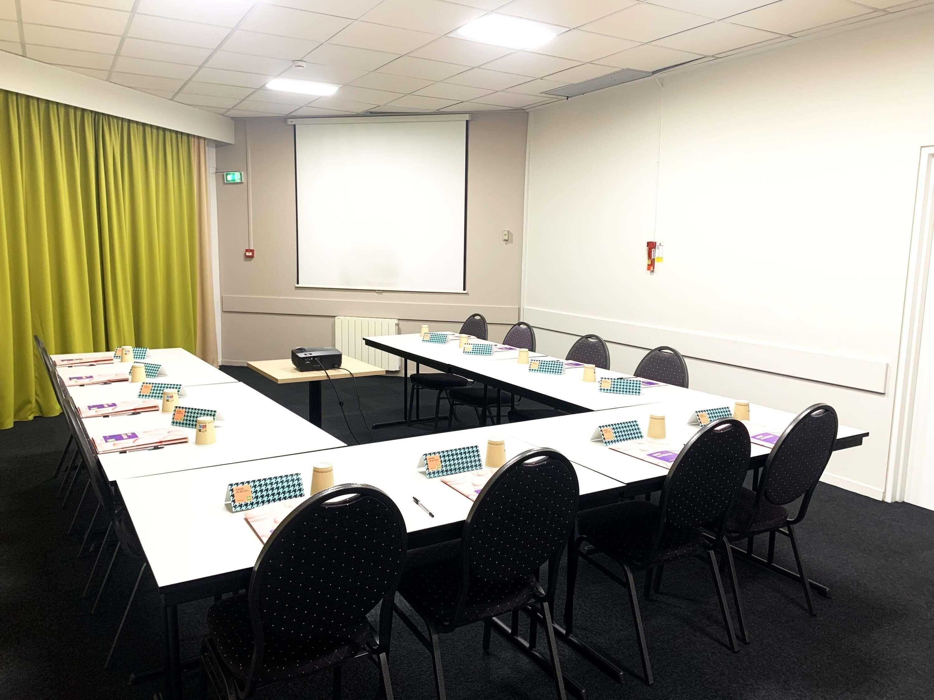A conference room with a long table, chairs, a projector, and a whiteboard.