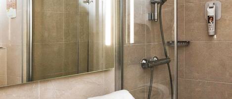 Un baño moderno con cabina de ducha de vidrio, un lavamanos con grifo y una toalla sobre la encimera.