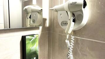 A hair dryer mounted on a wall with a charging cable.