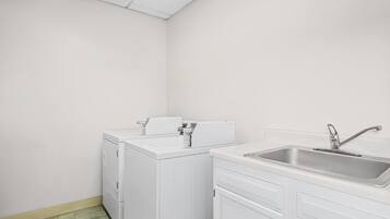 A small, clean laundry room with a washing machine, dryer, and sink.
