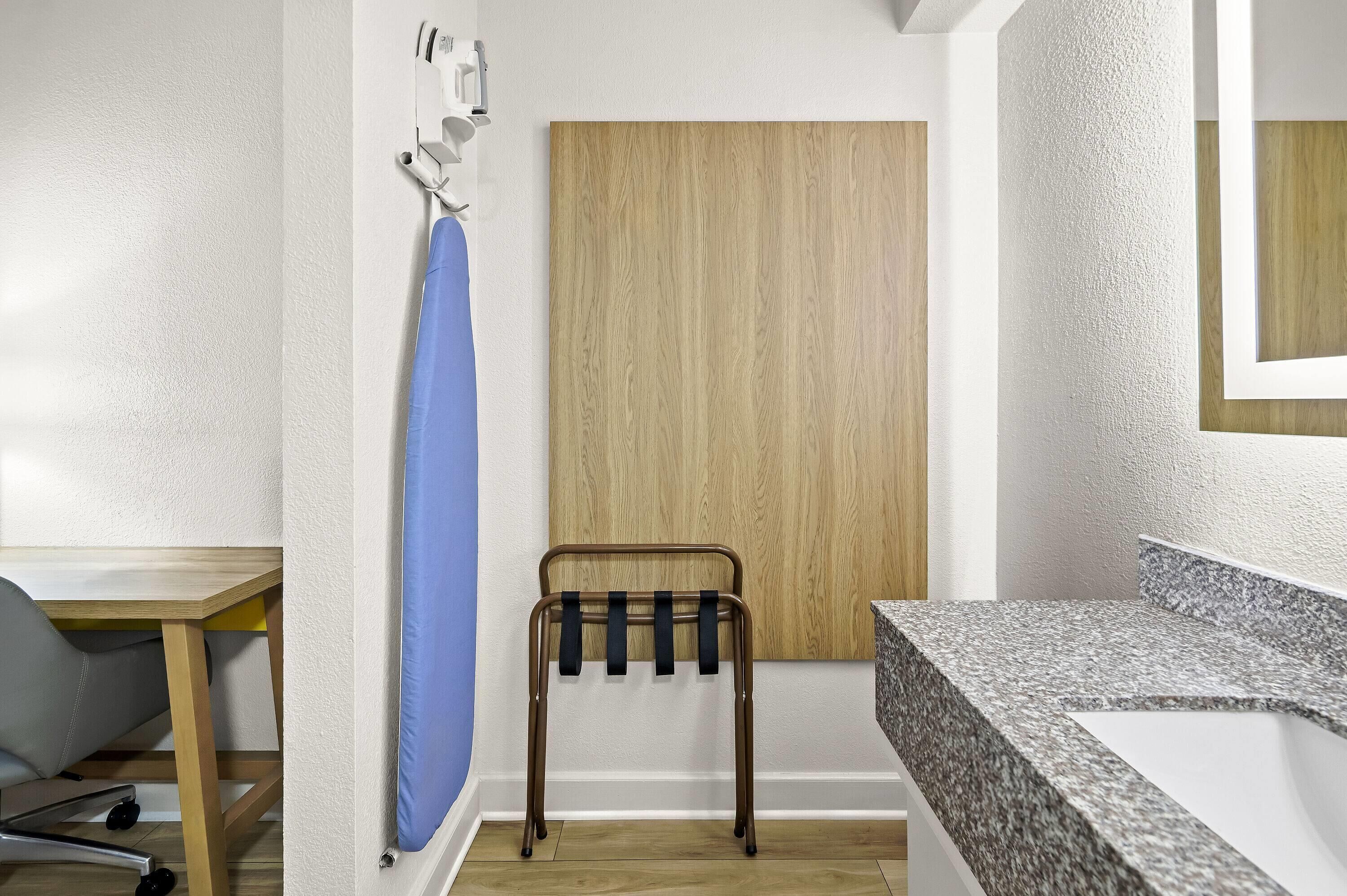A bathroom with a wooden panel wall, a sink with a granite countertop, and a metal towel rack.
