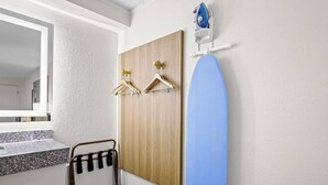 A bathroom with a wooden panel wall, a blue shower curtain, and a towel rack with hangers. - Days Inn by Wyndham Salem (Salem)