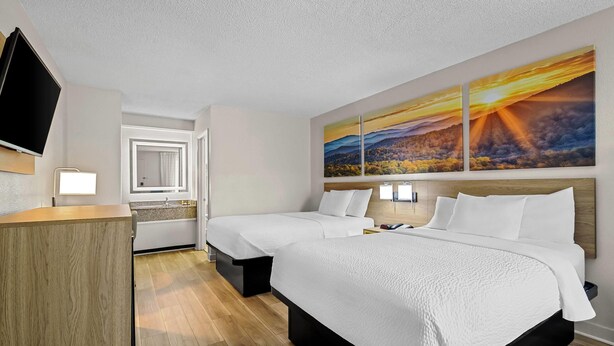 A hotel room with two beds, a TV, a desk, and a large landscape painting on the wall. - Days Inn by Wyndham Salem (Salem)