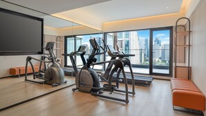 A modern gym with exercise equipment, a large mirror, and a view of the city through large windows. - Holiday Inn Express Shenzhen Luohu Port by IHG (Shenzhen)