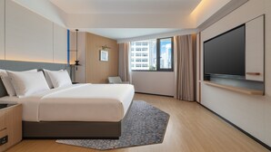 A modern hotel room with a large bed, a flat-screen TV, a desk, and a window with a city view. - Holiday Inn Express Shenzhen Luohu Port by IHG (Shenzhen)