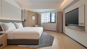 A modern hotel room with a large bed, a flat-screen TV, a desk, and a window with a city view. - Holiday Inn Express Shenzhen Luohu Port by IHG (Shenzhen)