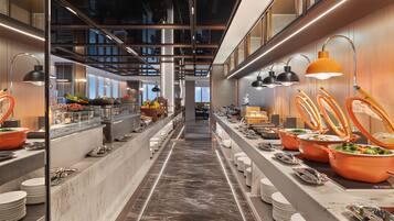 A modern buffet setup with multiple serving stations, a central walkway, and overhead lighting.