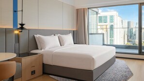 A hotel room with a bed, a desk, and a view of the cityscape through large windows. - Holiday Inn Express Shenzhen Luohu Port by IHG (Shenzhen)