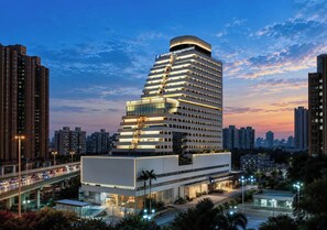 Un hotel de varios pisos con diseño moderno, que destaca por su parte superior curva y múltiples balcones.