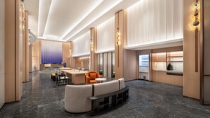 Un vestíbulo de hotel moderno con piso de mármol, zona de estar y kitchenette.