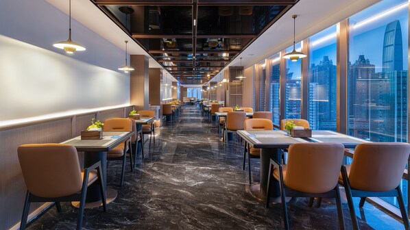 A modern dining area with tables and chairs, a marble floor, and large windows with a cityscape view. - Holiday Inn Express Shenzhen Luohu Port by IHG (Shenzhen)