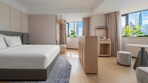 A modern hotel room with a large bed, a desk, and a view of the city skyline. - Holiday Inn Express Shenzhen Luohu Port by IHG (Shenzhen)