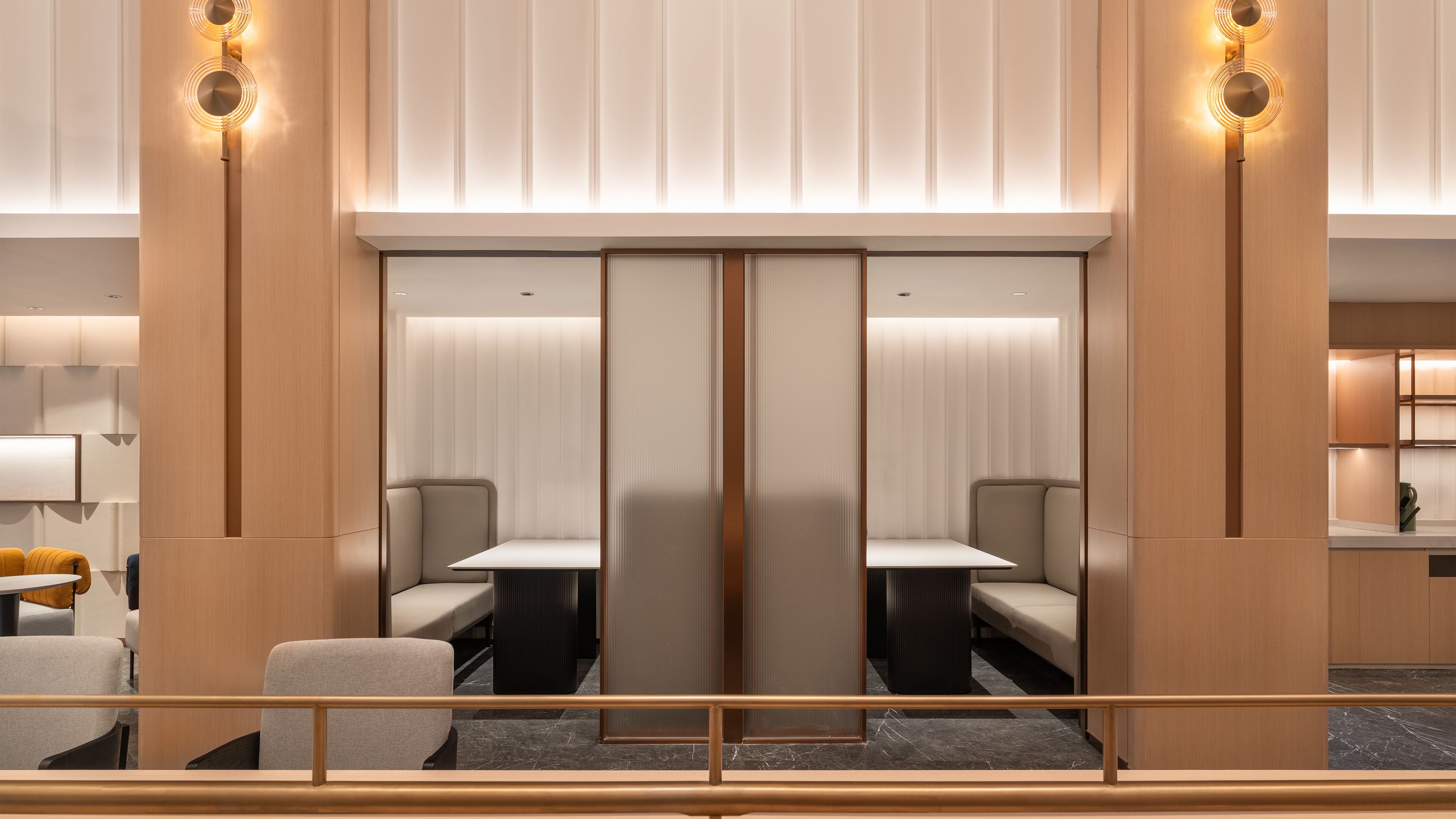 A modern hotel lobby with a seating area, a large mirror, and a wooden partition.