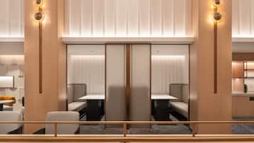 A modern hotel lobby with a seating area, a large mirror, and a wooden partition.
