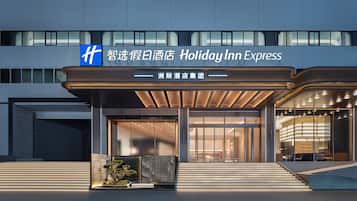 A modern hotel entrance with a covered walkway, large glass doors, and a sign indicating it's a Holiday Inn Express.