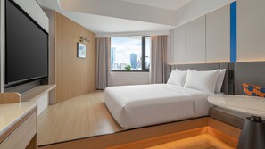 Habitación de hotel con cama, escritorio, televisor y ventana con vistas a la ciudad.