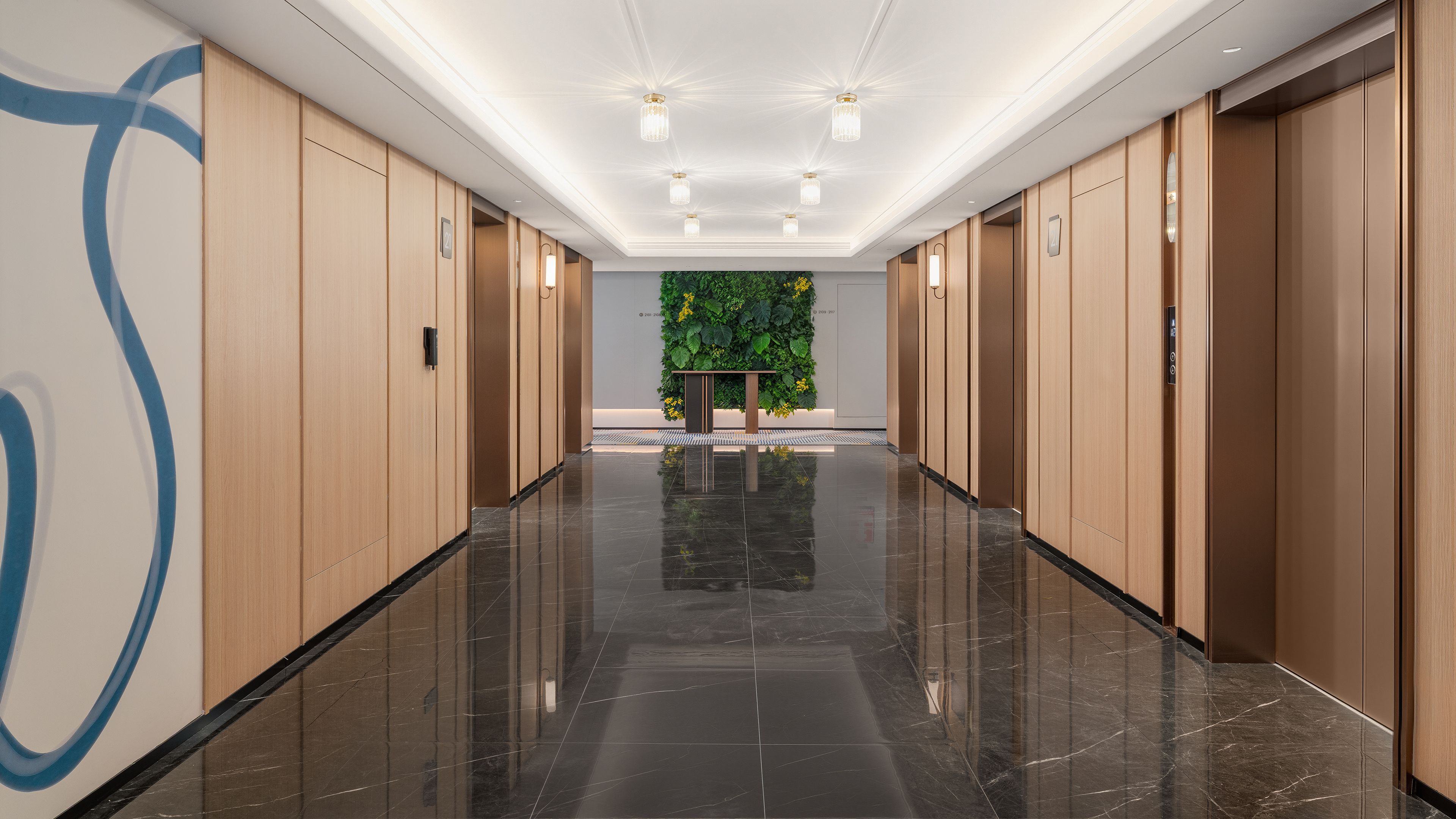 A modern hotel hallway with wooden paneling, a marble floor, and a green wall with plants.