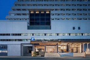Un moderno edificio de hotel con una entrada destacada, ventanas amplias y un letrero que indica que es un Holiday Inn Express.
