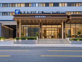 A Holiday Inn Express hotel entrance with a modern design, featuring a prominent sign and a well-lit facade.