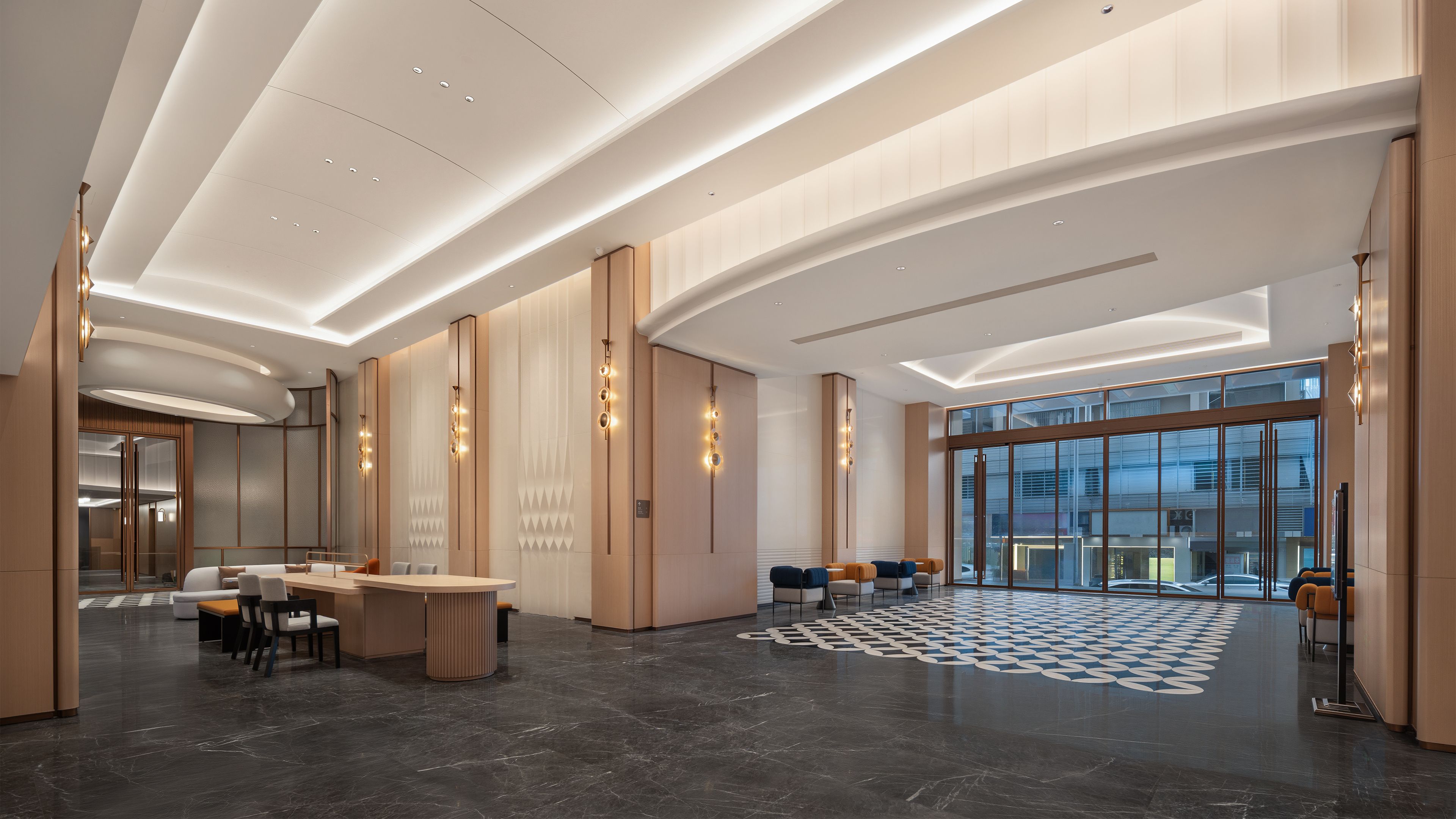 Een moderne hotellobby met een receptiebalie, een zithoek en grote ramen met uitzicht op de stad.
