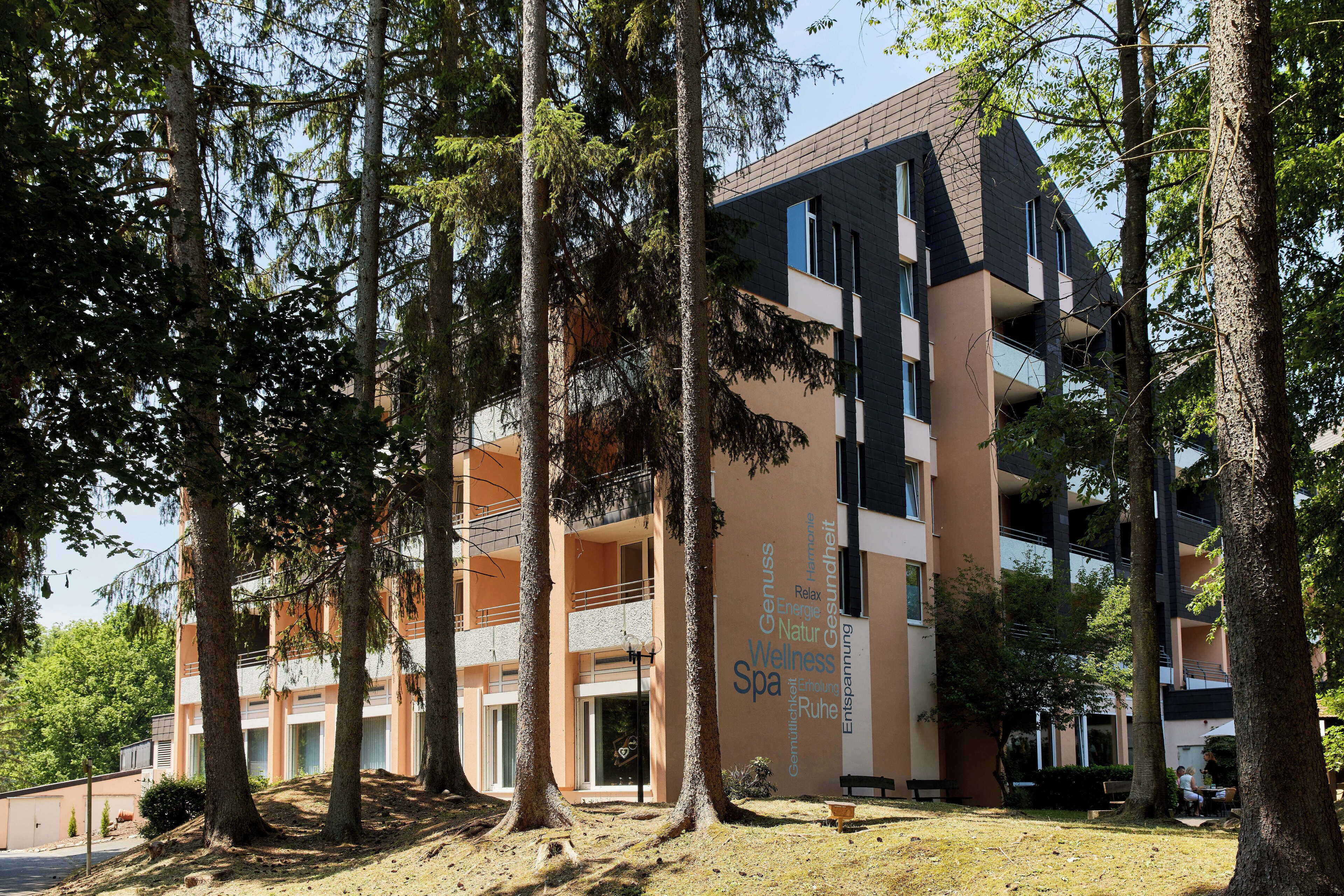 A multi-story building with balconies, surrounded by trees.