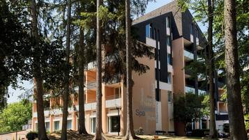 A multi-story building with balconies, surrounded by trees.