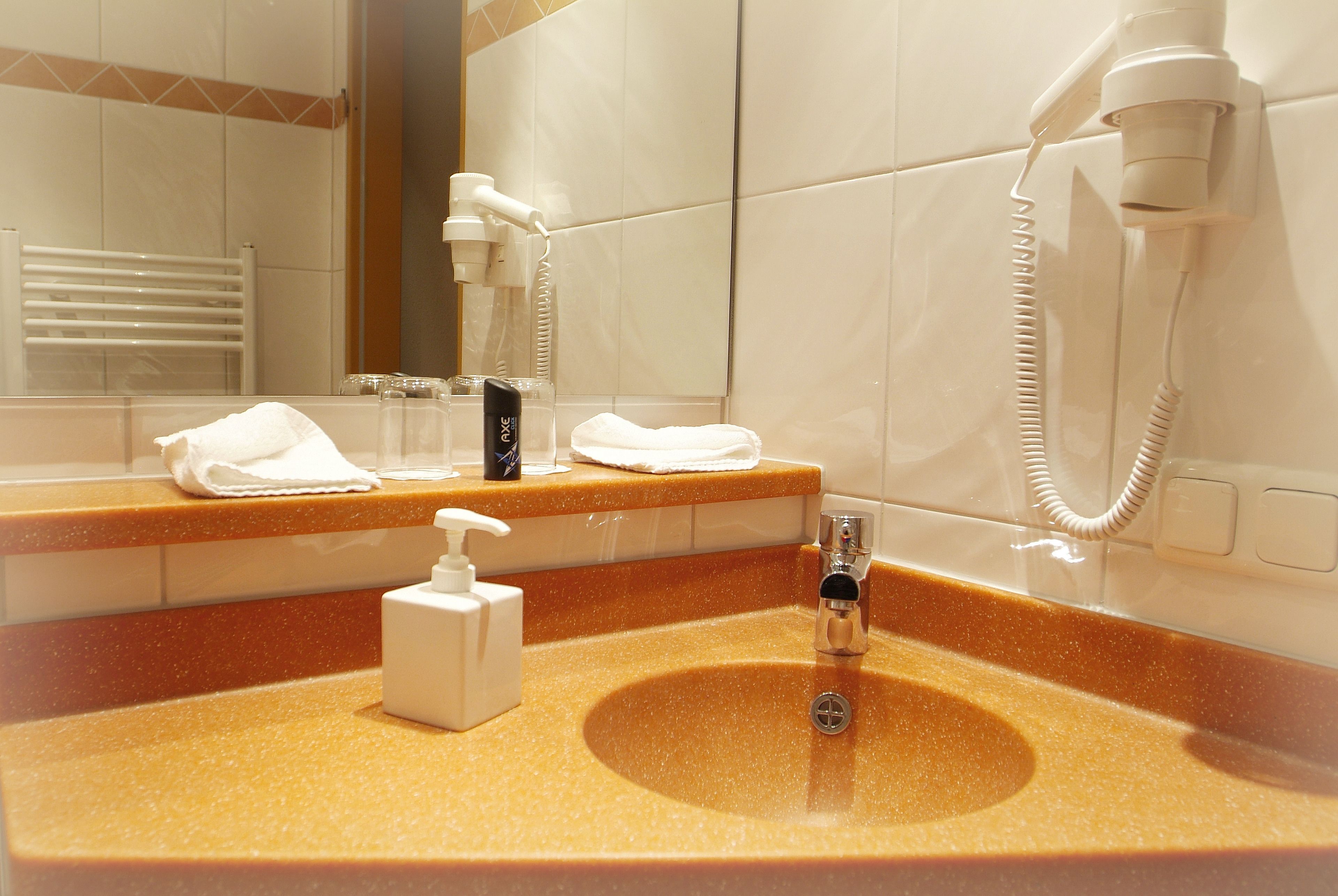 Un baño con lavamanos, dispensador de toallas y secador de pelo montado en la pared.