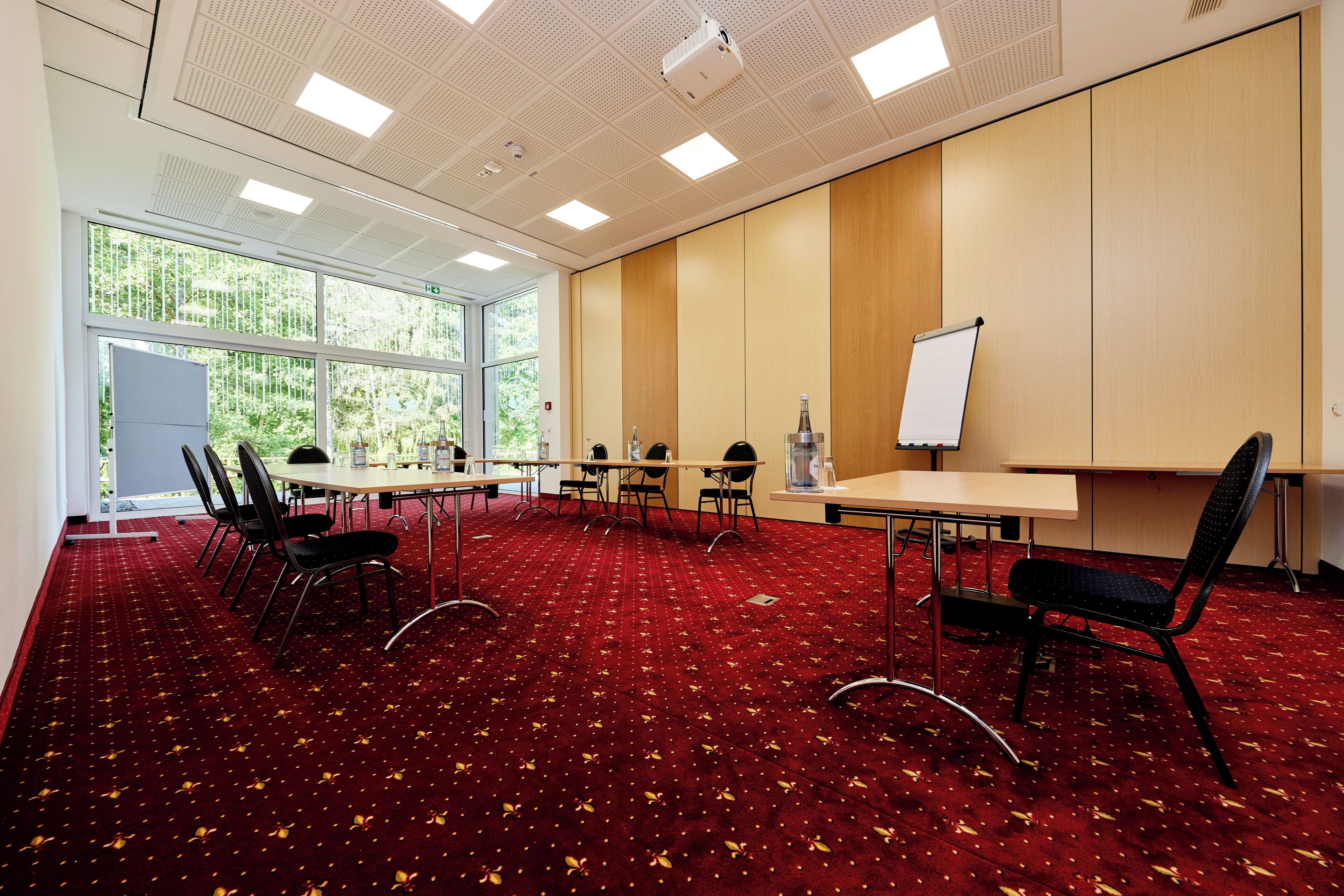 Ein Konferenzraum mit rotem Teppich, einer Whiteboard und großen Fenstern.