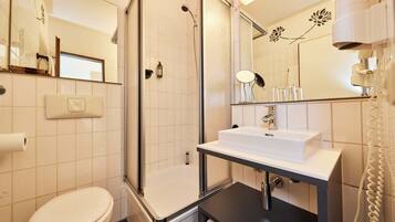 A modern bathroom with a toilet, a shower with a glass door, a sink with a mirror, and a towel rack.