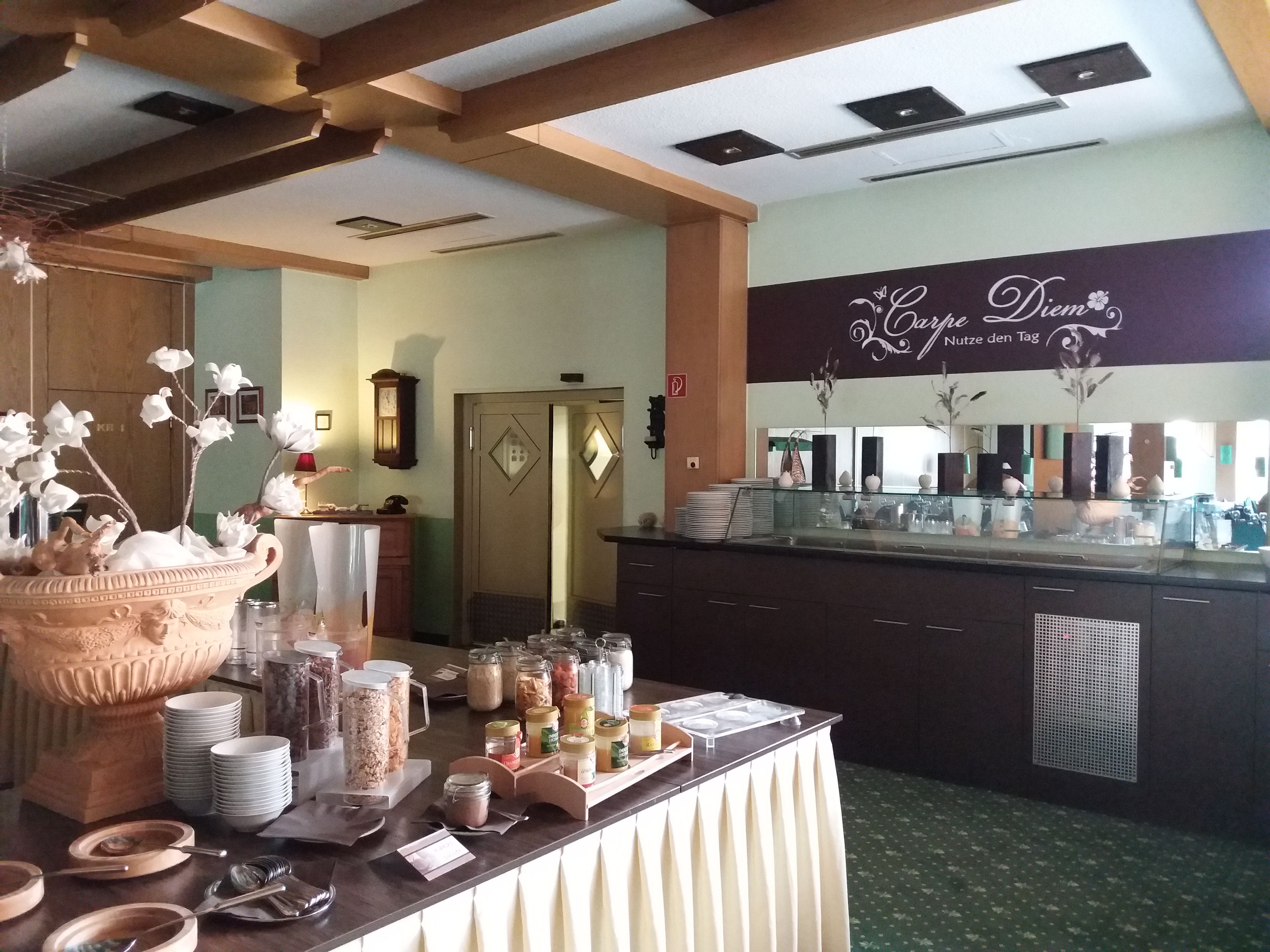 A buffet setup with a variety of food items and condiments, a clock on the wall, and a decorative vase with flowers.