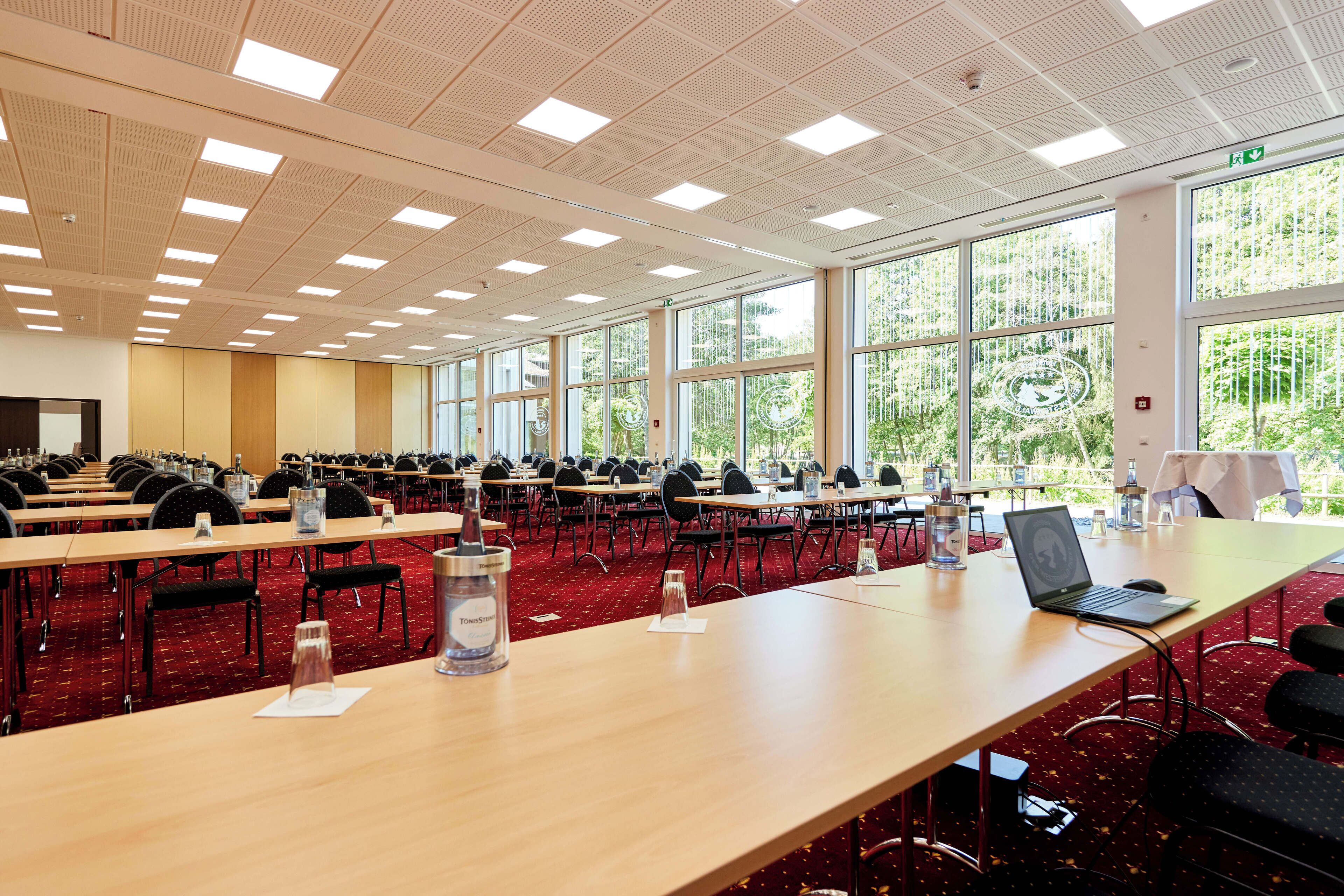 A conference room with multiple tables, chairs, and a laptop on one table.