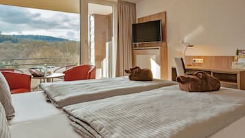 Habitación de hotel con dos camas, televisión, escritorio y vistas al exterior.