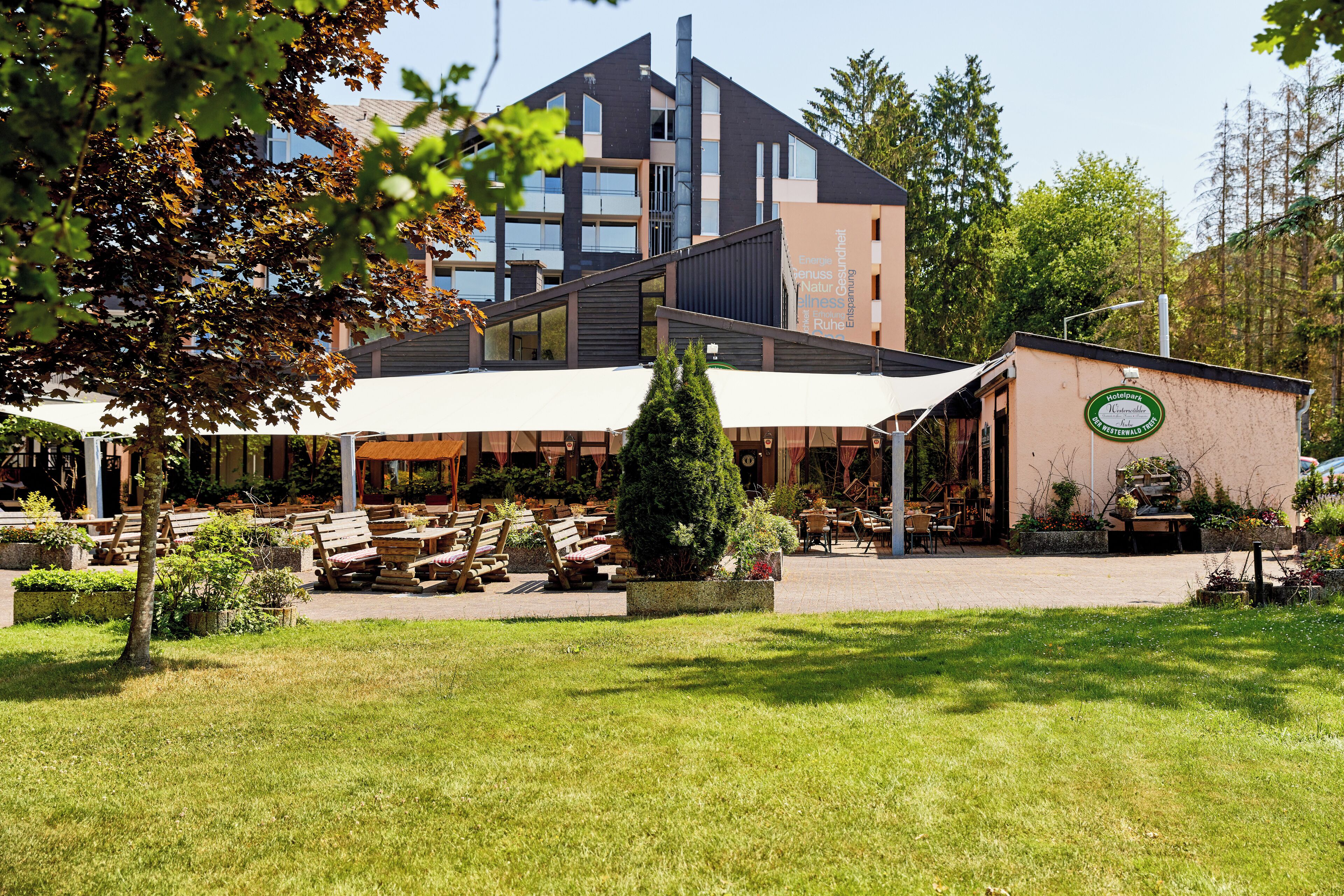 Ein modernes Gebäude mit Außenbestuhlung und einem Gartenbereich.