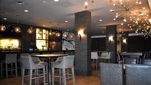 A modern bar area with high stools, a bar counter, and pendant lighting.