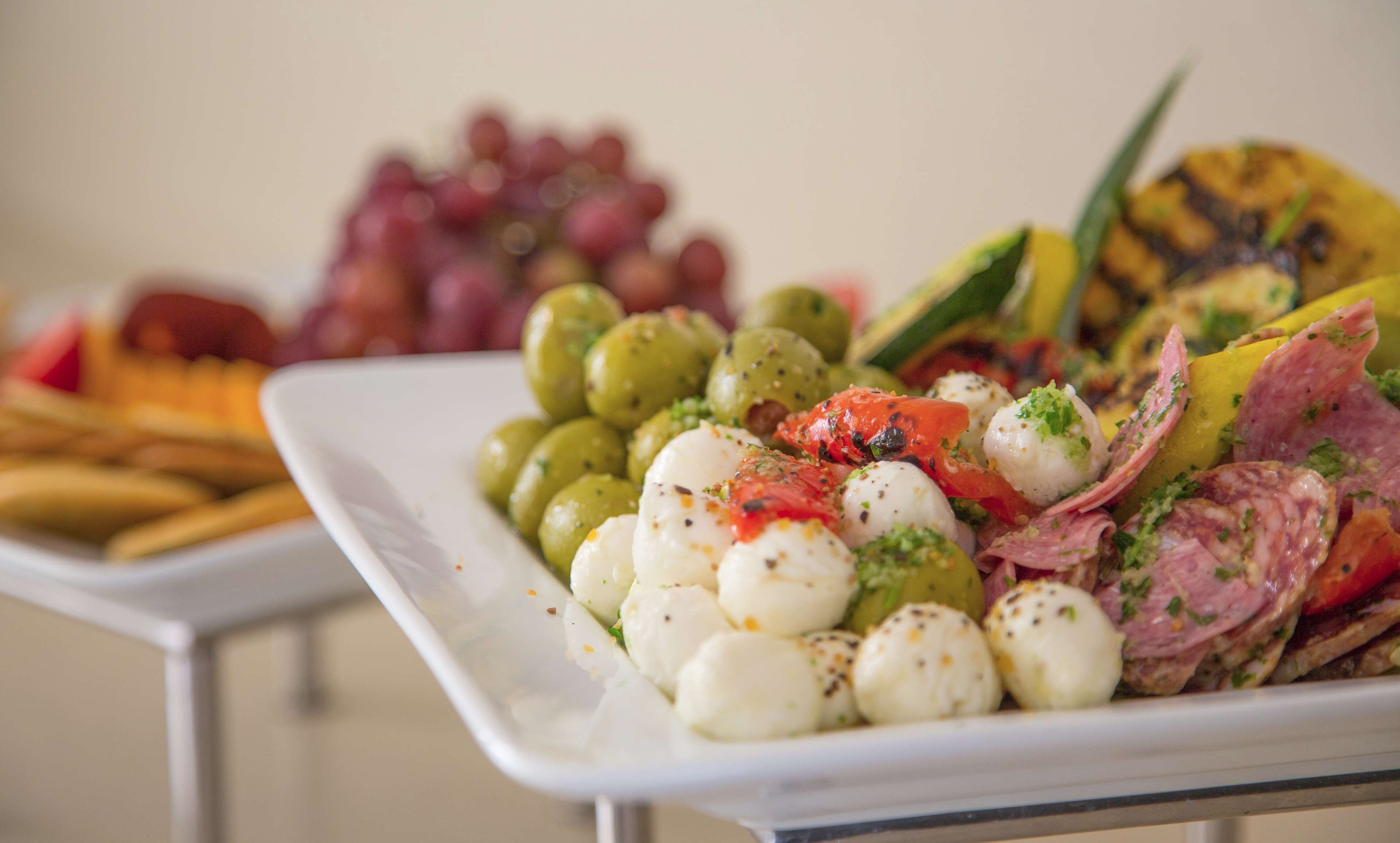 A plate of food with olives, mozzarella balls, and sliced meats.