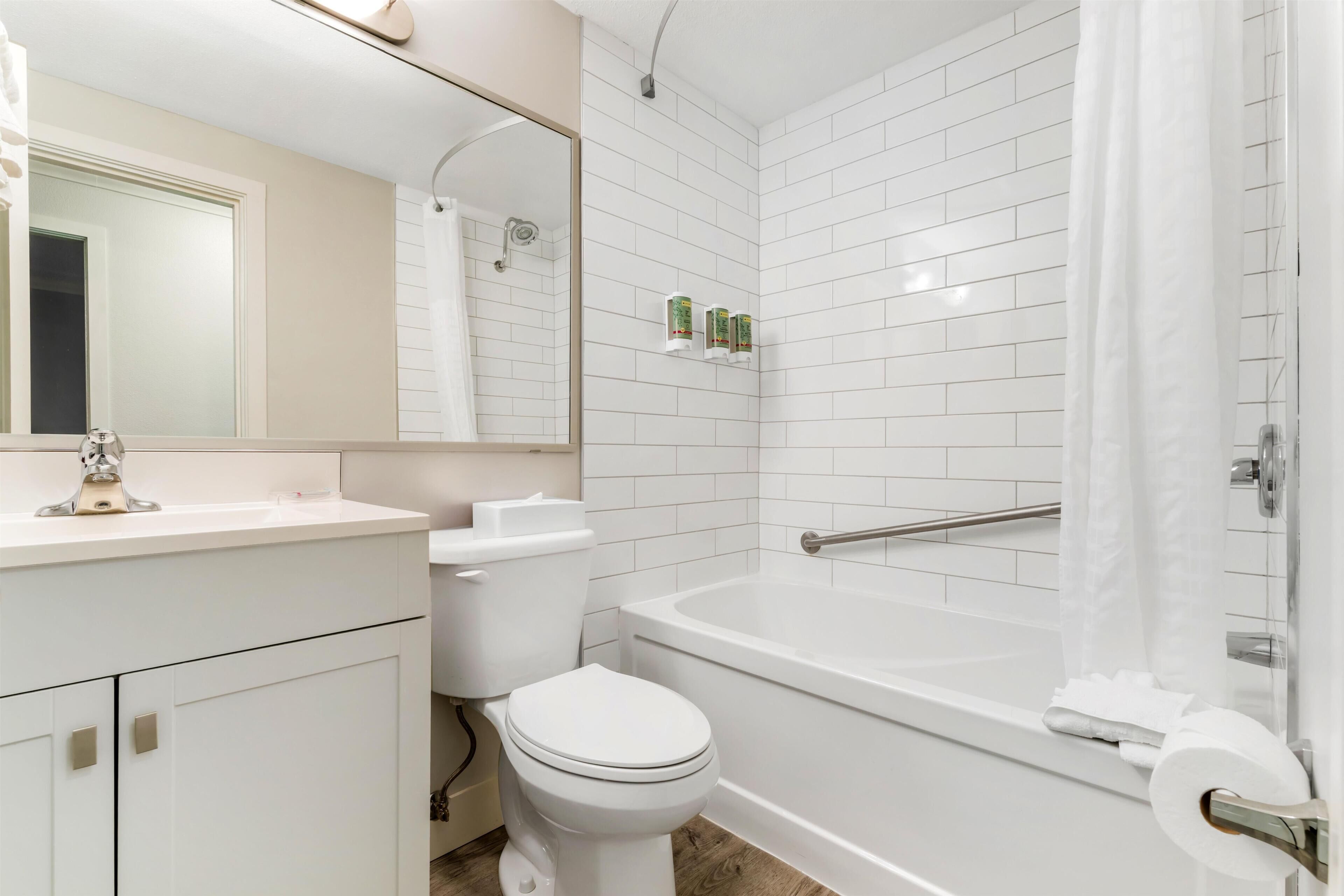 Un baño con inodoro, lavamanos, espejo, ducha y bañera.